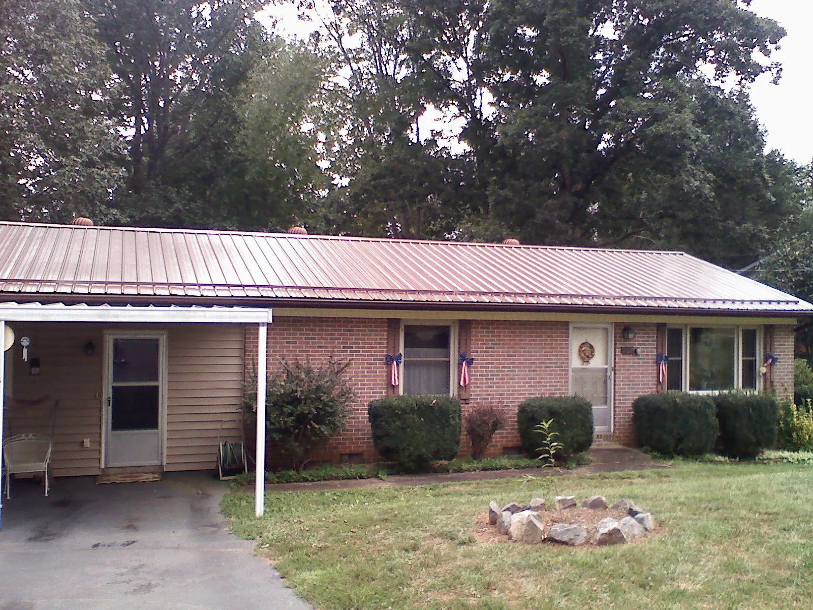 Bronze metal roof and carport on a brick ranch home — Roof Repair work by our crew in Rawlings